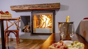 A cozy room with a fireplace, a wooden table with a tray of food, and a chair.
