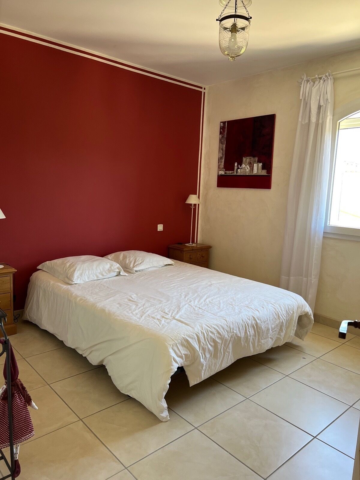 Une chambre avec un lit simple, une table de chevet, une lampe et une fenêtre avec des rideaux.
