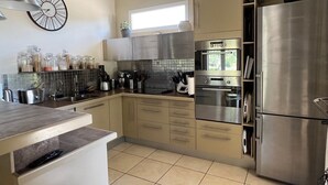 A modern kitchen with stainless steel appliances, a central island, and pendant lighting. - Villa de Charme, à Proximité Immédiate D'uzes et du Pont du Gard (Argilliers)