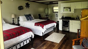 A bedroom with two beds, a small kitchenette, and a wooden chair. - Birch Point Resort Kitchenette #14 - Lake Nelson, Hayward (Hayward)