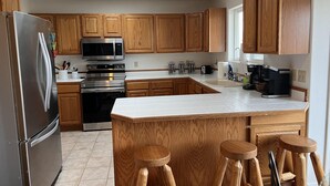 Una cocina moderna con armarios de madera, electrodomésticos de acero inoxidable, una isla grande con taburetes y un tragaluz.