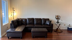 Una sala de estar con un sofá modular, una mesita de noche con un globo terráqueo y una lámpara de pie.