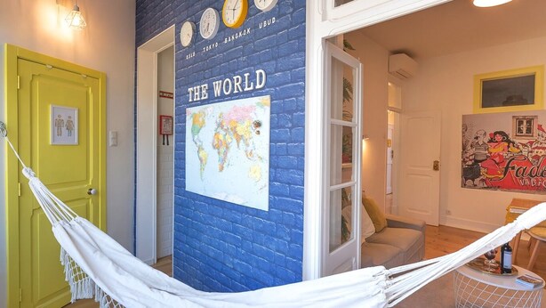 A room with a hammock, a basketball hoop, a world map, and a door with a yellow frame.