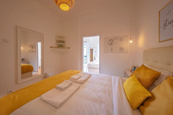 A hotel room with a large bed, a bedside table, a mirror, and a wall-mounted light fixture.