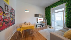 A modern living space with a dining area, a TV, and a green wall.