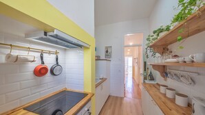 A kitchen with white tiled walls, wooden countertops, and a yellow accent wall.