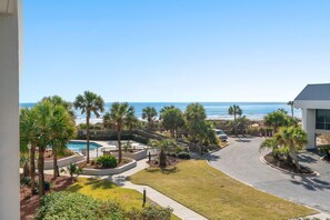 A residential area with a swimming pool, palm trees, and a view of the ocean.