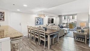 Una sala de estar moderna con comedor, piso de madera y un gran ventanal con vistas a la ciudad.