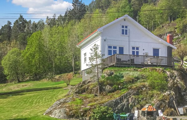 Een wit huis met balkon, omringd door groen en bomen.