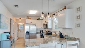 A modern kitchen with white cabinets, granite countertops, and pendant lighting. - "Sea Drift" Steps to the White Sand Beaches! Close to Restaurants, Coffee Shops! (Navarre)