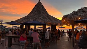 A beachside bar with thatched umbrellas and wooden deck. - "Sea Drift" Steps to the White Sand Beaches! Close to Restaurants, Coffee Shops! (Navarre)