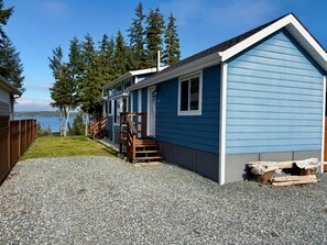 A row of blue cabins with a gravel driveway and wooden steps leading to the entrance.