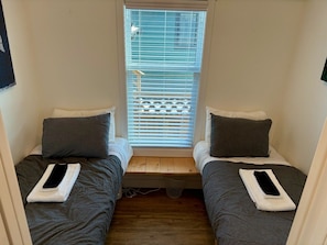 A small room with two beds, each with a pillow and a folded towel.