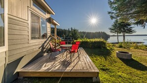 Una terraza de madera con muebles de exterior, una parrilla y una vista panorámica del lago.
