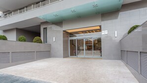 Ein moderner Gebäudeeingang mit Glastür, Nummernschildern und einem überdachten Bereich mit Metalldach.