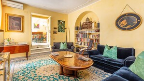 A living room with a wooden coffee table, a blue sofa, a bookshelf, and a large rug.