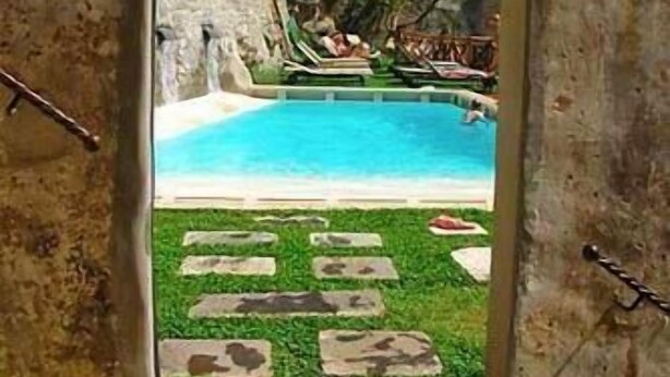 Una puerta que da a una zona de piscina con un muro de piedra y un césped.