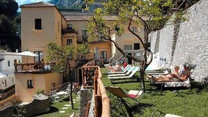 Un patio con sillones de descanso, una pequeña piscina y un muro de piedra.
