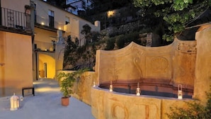 Un patio con una fuente, plantas en macetas y un edificio con balcones.