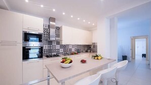 A modern kitchen with white cabinets, a built-in oven, and a patterned backsplash. - Modern Apartment close to the Beach - Corso 4 by AMALFIVACATION.IT (MINORI)