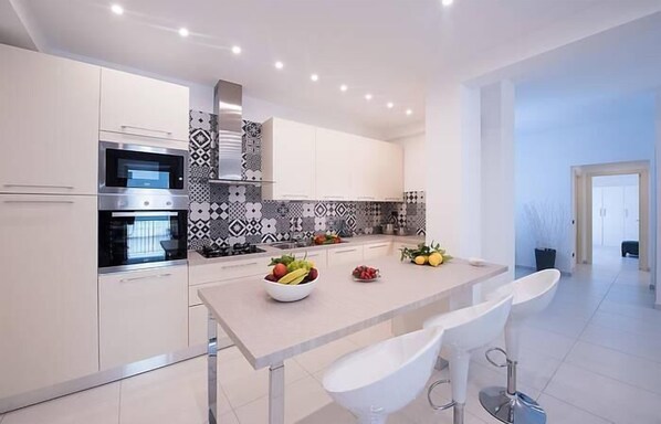 Una cocina moderna con armarios blancos, horno empotrado y un salpicadero con diseño.