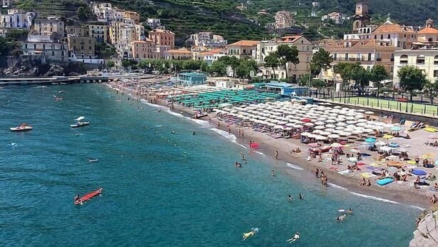 A coastal town with a beach, buildings, and a mountainous backdrop. - Modern Apartment close to the Beach - Corso 4 by AMALFIVACATION.IT (MINORI)