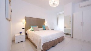 A modern bedroom with a large bed, bedside tables, a wardrobe, and a chandelier. - Modern Apartment close to the Beach - Corso 4 by AMALFIVACATION.IT (MINORI)