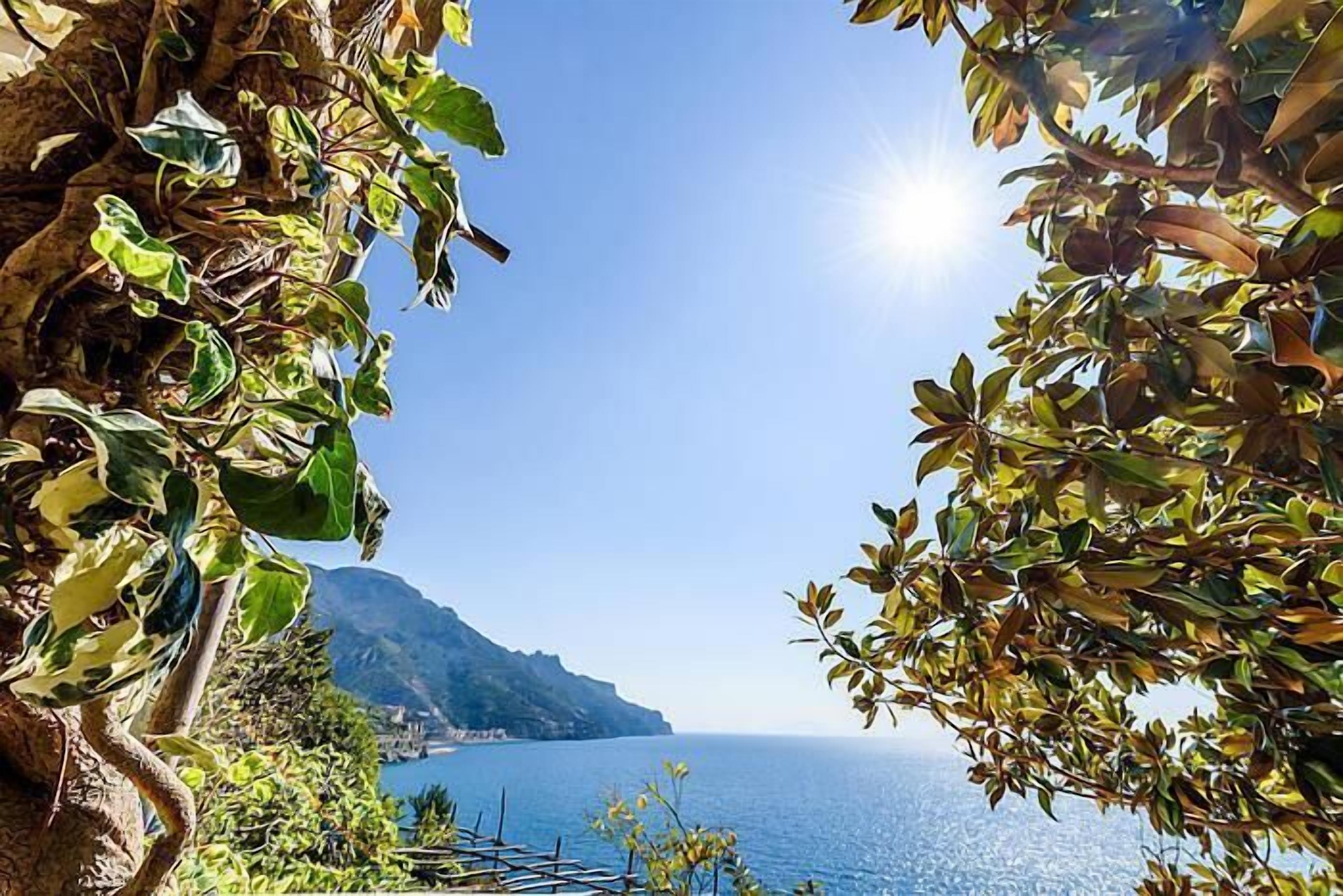A coastal view with a clear sky, a body of water, and a mountainous landscape in the distance.