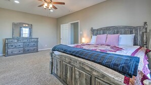 A bedroom with a wooden bed, a dresser, a ceiling fan, and a door. - Peaceful Atascosa Home w/ Balcony & Deck! (Atascosa)