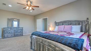Une chambre avec un lit en bois, une commode, un ventilateur de plafond et une porte.