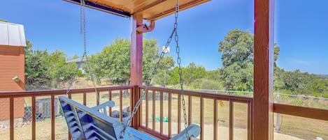 A wooden deck with a swing set and a covered area.