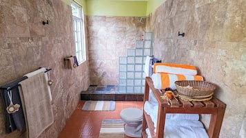 Un bagno con doccia, WC e una panca in legno con asciugamani.