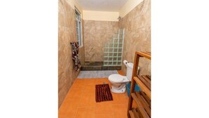 Une petite salle de bain avec des toilettes, une douche et un sol carrelé.