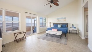 A bedroom with a bed, a nightstand, a desk, a chair, and a ceiling fan.