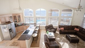 A spacious living area with a kitchen, large windows, and a view of the sea.