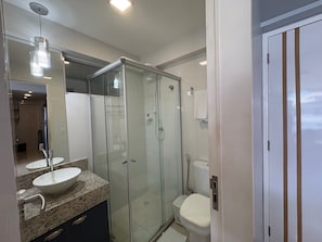 A modern bathroom with a glass-enclosed shower, a granite countertop, and a white toilet.