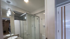 A modern bathroom with a glass-enclosed shower, a granite countertop, and a white toilet. - Imperial Bessa (João Pessoa)