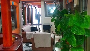 Un hall de hotel con piso a cuadros, un sofá, una planta grande en maceta y una escalera.