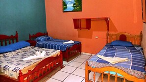 Una habitación con dos camas de madera con cabeceros rojos, una mesita de madera y un estante fijado a la pared.