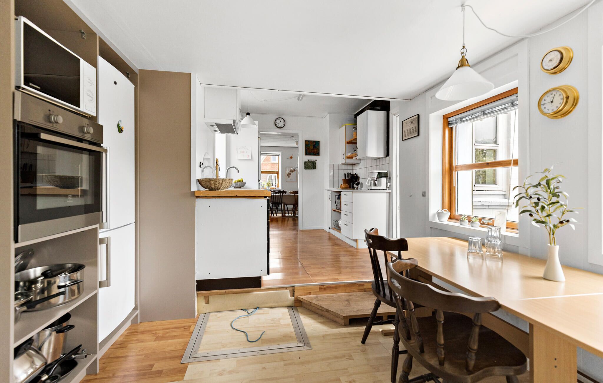 A modern kitchen with a wooden dining table, built-in oven, and white cabinetry.