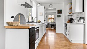Une cuisine moderne avec des meubles blancs, un plan de travail en bois et une vue sur la salle à manger.