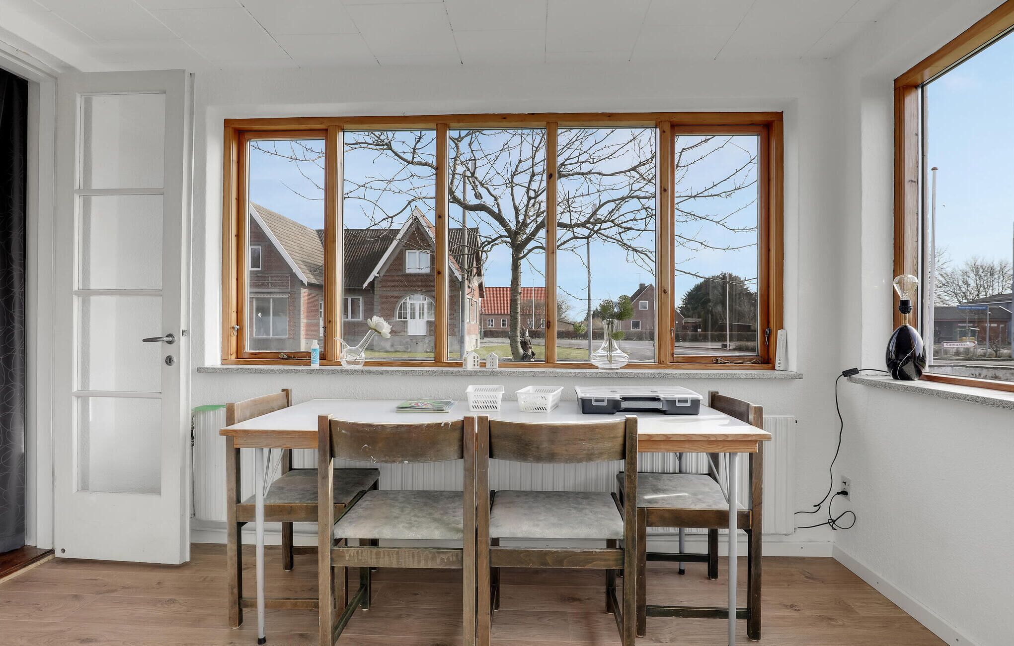 A dining area with a large window, wooden table, and chairs.