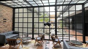 A spacious room with a high ceiling, exposed wooden beams, and a large glass wall providing a view of the outdoor area. - R4/ Artistic Loft in historic Candelaria (Bogotá)