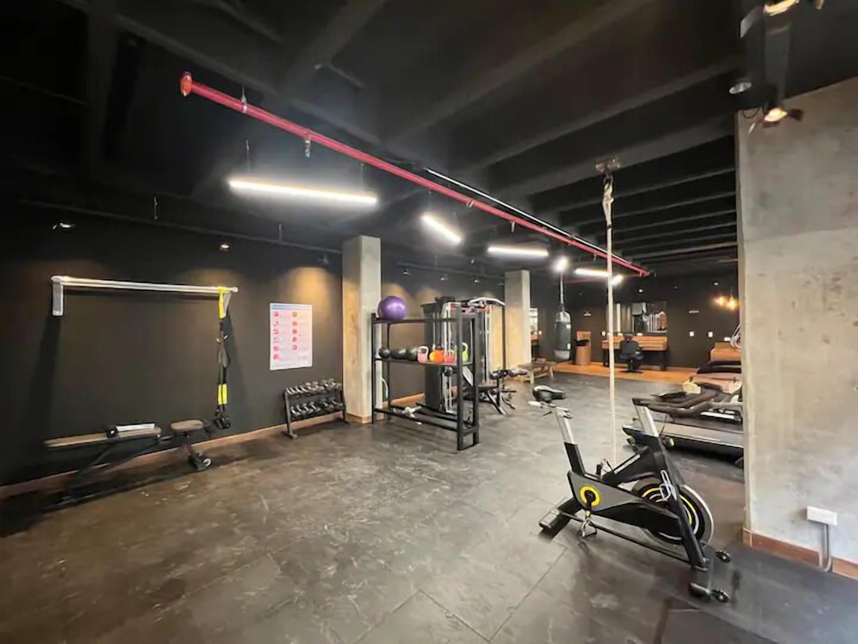 Un gimnasio con equipo de ejercicio, una barra de dominadas y un soporte de pared para pesas.