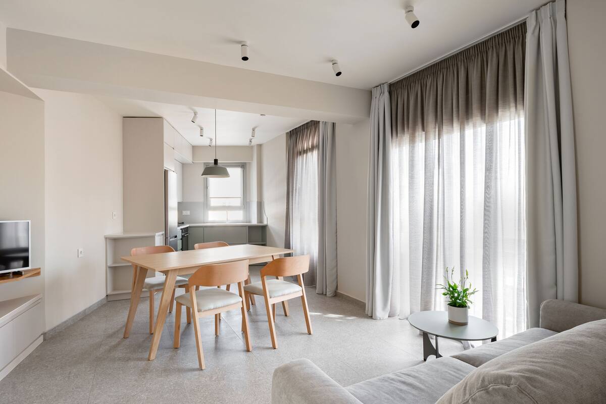 Una sala de estar moderna con comedor, un sofá, un televisor y una mesita con una planta.