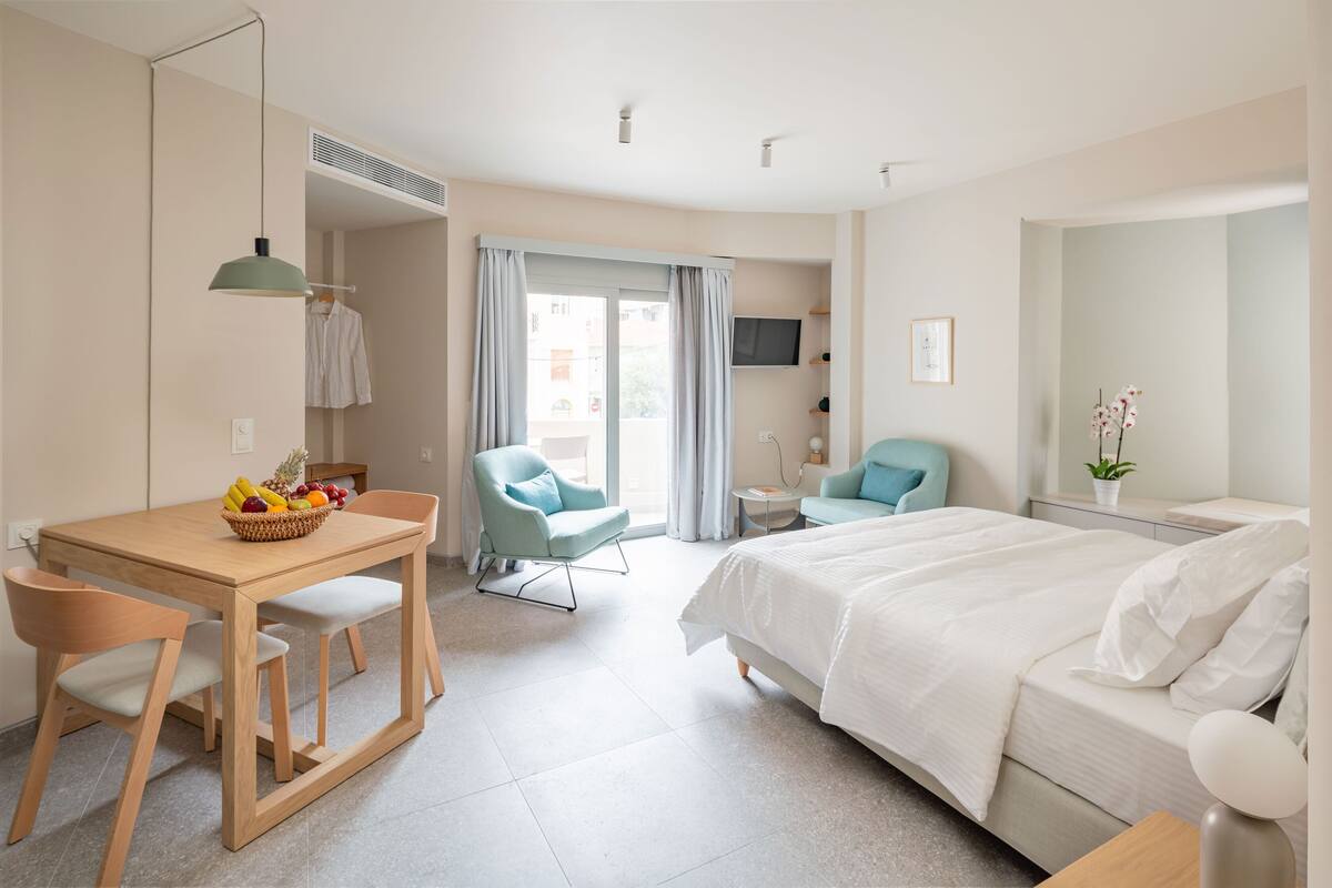 Una habitación de hotel con una cama, un escritorio con silla, una mesa de comedor y un televisor.