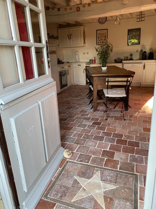 A kitchen with white cabinets, a wooden table, and a star-patterned tile floor.
