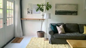 Un salon avec un canapé gris, une plante en pot et un tableau accroché au mur.