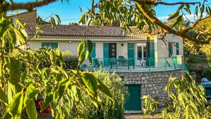 A two-story house with a stone foundation, a balcony with green railings, and a green door. - Cozy apartment in Ginasservis with swimming pool (Ginasservis)