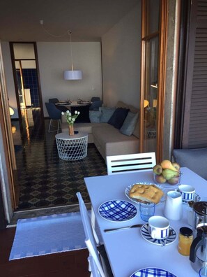 Enjoy a meal in our outdoor dining area, where a table is set with plates, cups, and a coffee pot, accompanied by a bowl of fresh fruit.